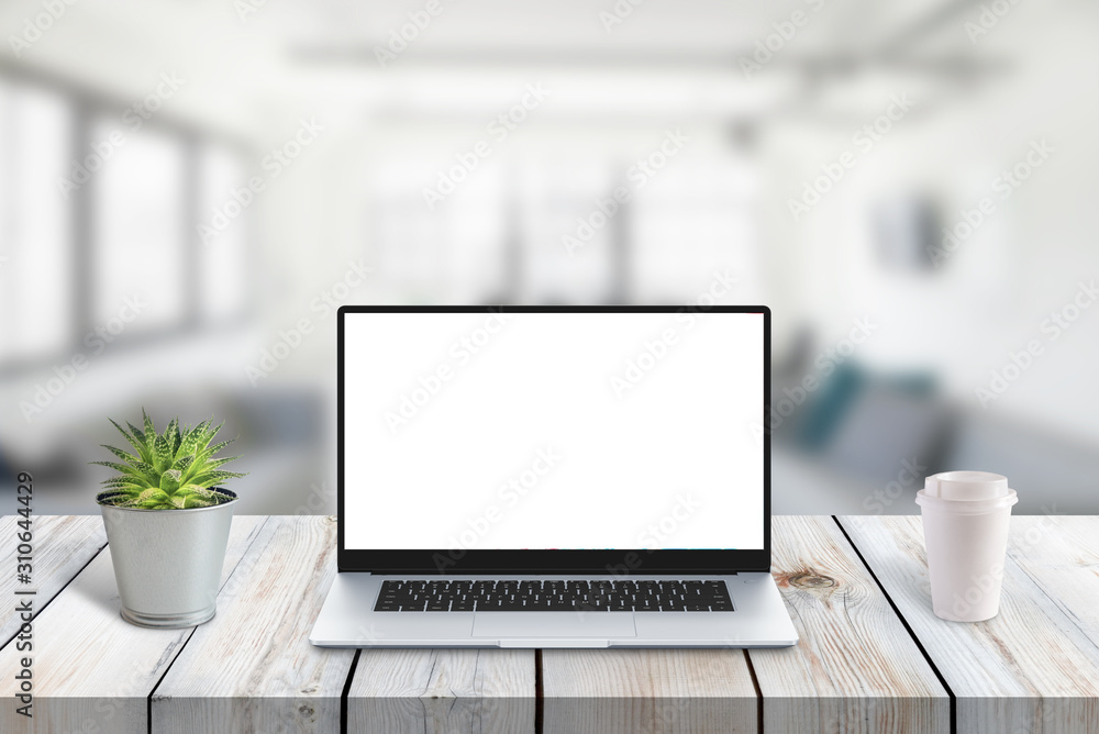 Laptop computer on wooden desk with isolated screen for app or web site promotion. Office in background. Plant and cup of coffee on desk