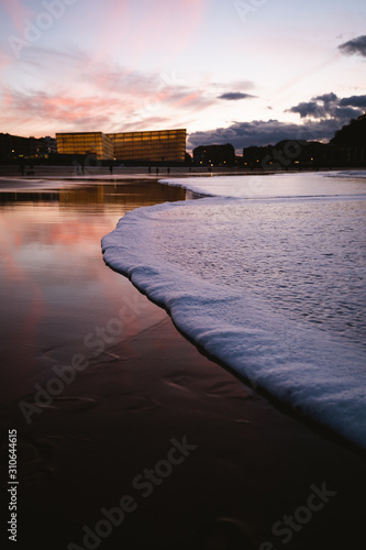 Foamy seashore of Zurriola Beach in San Sebastian after sunset