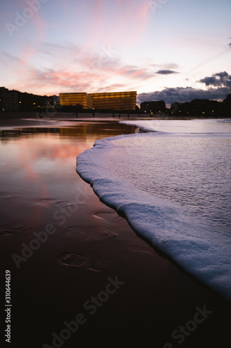 Foamy seashore of Zurriola Beach in San Sebastian after sunset