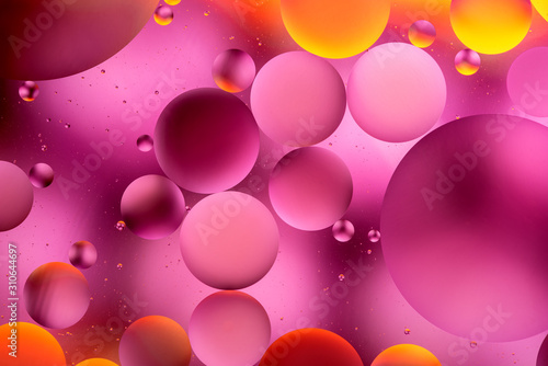 orange and pink oily drops in water with colorful background, close-up 