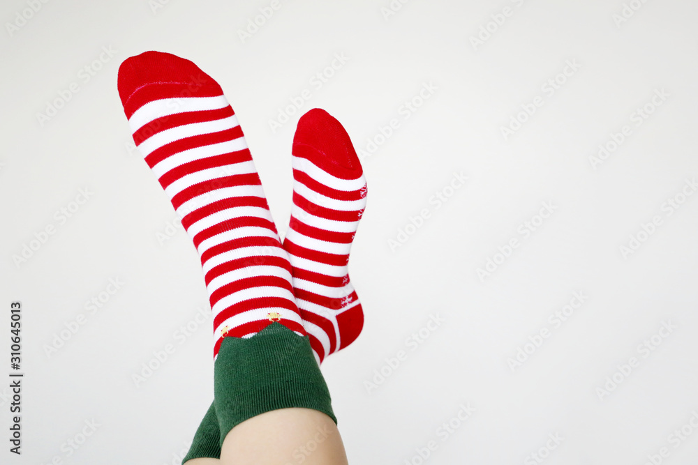 Female feet in Christmas socks on white background. Concept of New Year celebration, female santa, elf costume Female feet in Christmas socks on white background. Concept of New Year celebration, female santa, elf costume