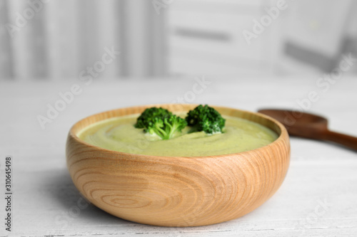 Delicious broccoli cream soup served on white wooden table