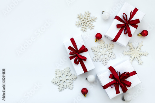 Gift boxes wrapped white paper and red ribbon decorated bubles and snowflakes on white background. Top view. Flat lay. Christmas and New Year