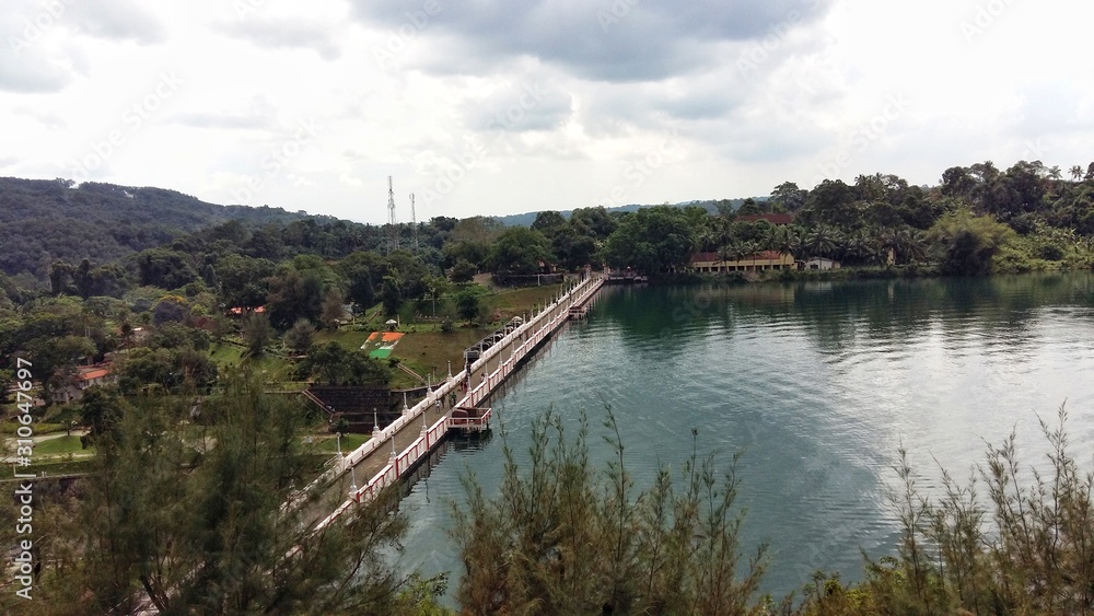 A view of dam filled with greenish appearing water with greenery around. Place : Neyyar Dam, Kerala, India