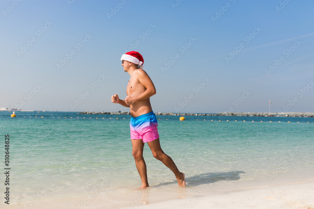 Young man in santa hat running in sea water, Vocation.