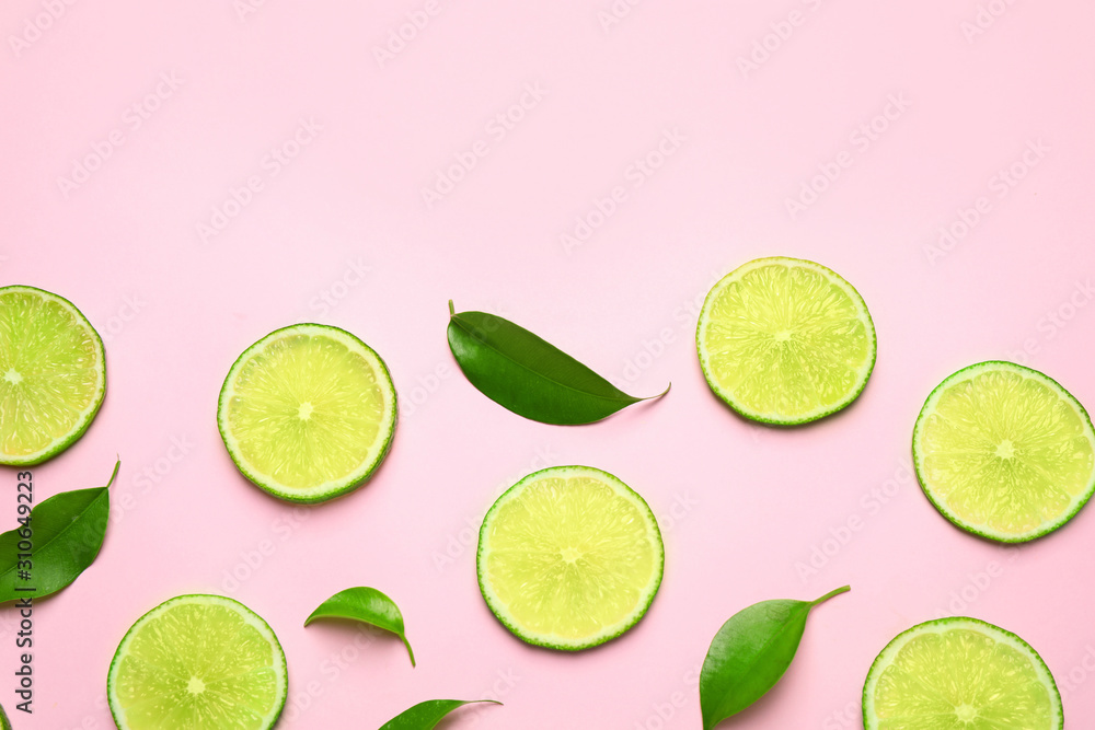 Juicy fresh lime slices and green leaves on pink background, flat lay. Space for text