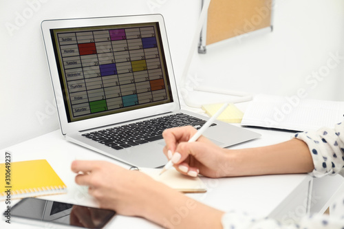 Woman planning her schedule with calendar app on laptop in office, closeup