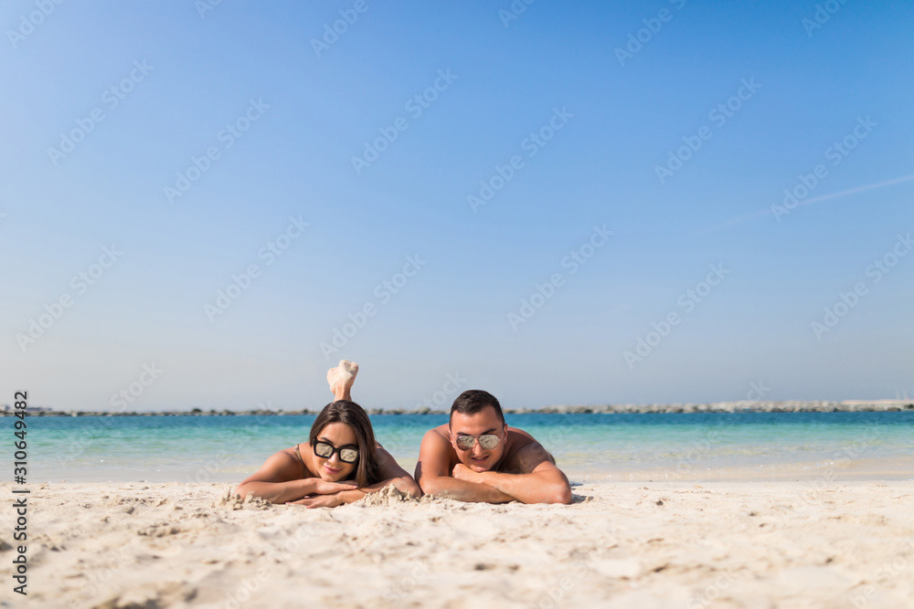 Happy young couple lying on a tropical beach