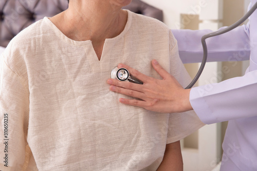 doctor listening to elderly patient's heart