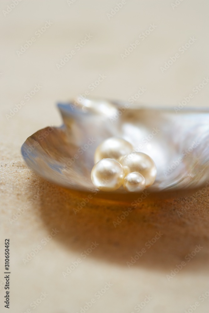 Four pearls in open oyster shell on beach close up Four pearls in open oyster shell on beach close up