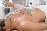 Young man undergoing laser epilation procedure in beauty salon, closeup