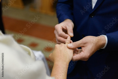 the bride and groom during the wedding ceremony put wedding rings on their fingers