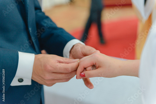 the bride and groom during the wedding ceremony put wedding rings on their fingers