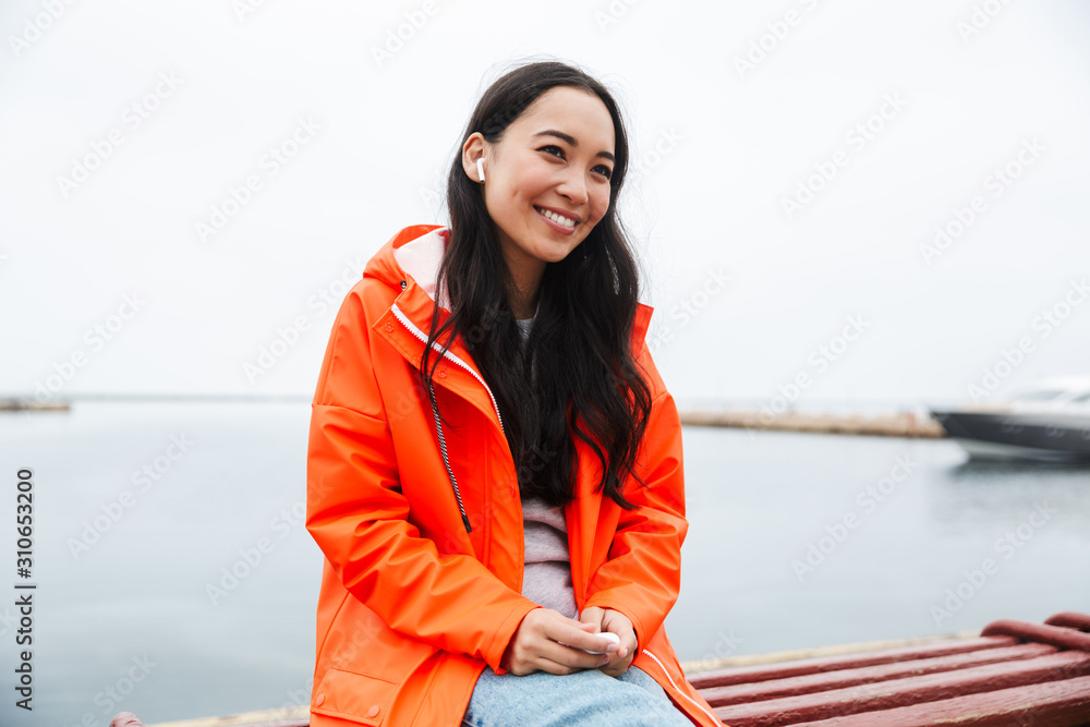 Obraz premium Smiling attractive young asian woman wearing raincoat