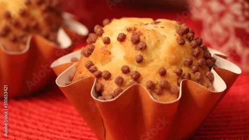 Christmas chocolate muffin. Sweet pastry, delicious healthy food for dessert, meal, breakfast. Closeup baked homemade cake next to red cups of hot coffee. Tasty fresh biscuit for celebration. 