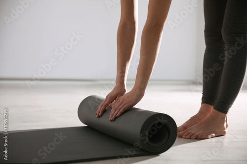 Woman rolling yoga mat in studio, closeup