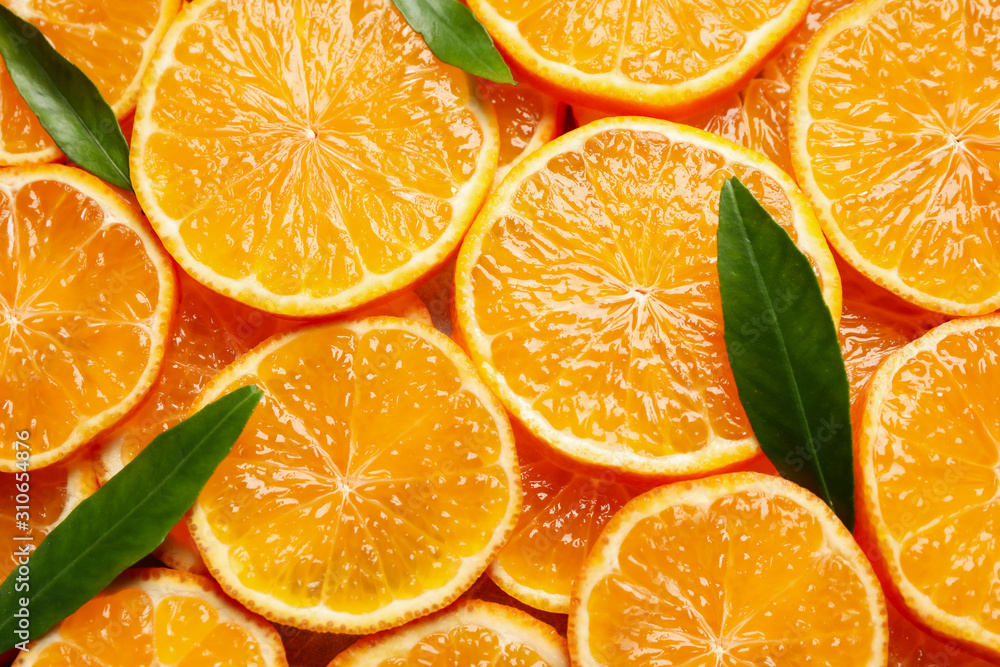 Slices of fresh ripe tangerines and leaves as background, top view. Citrus fruit Slices of fresh ripe tangerines and leaves as background, top view. Citrus fruit