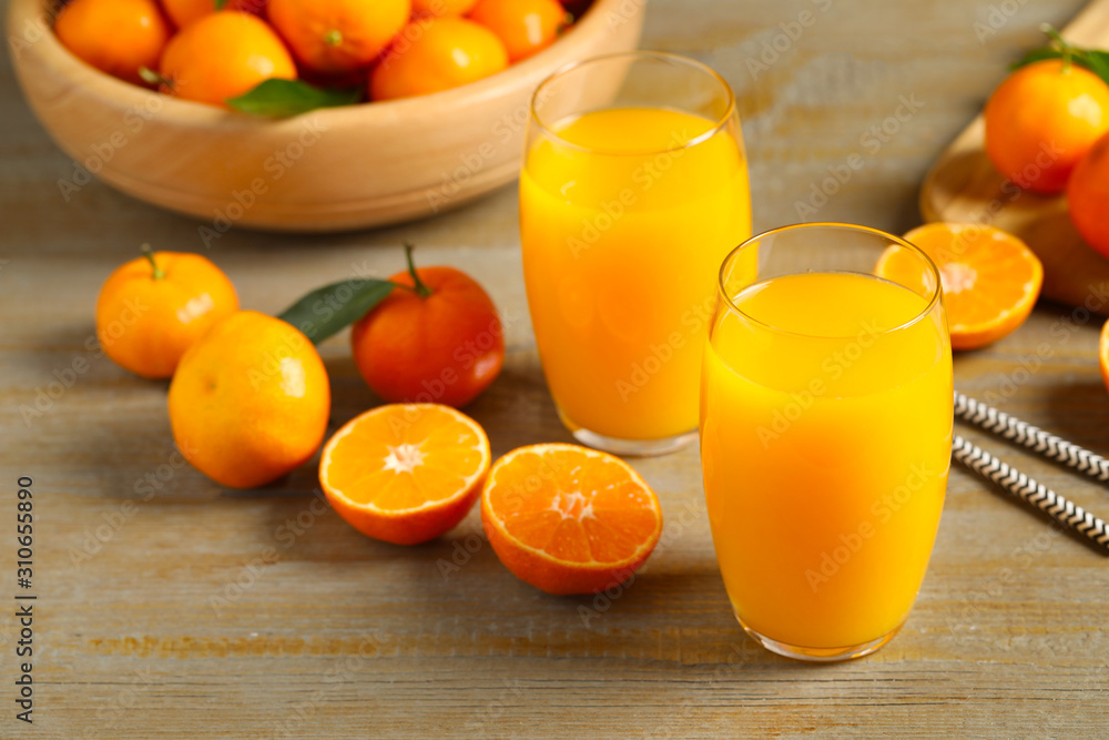 Glasses of fresh tangerine juice and fruits on wooden table Glasses of fresh tangerine juice and fruits on wooden table