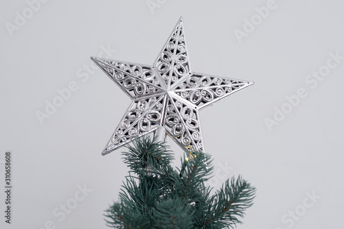 Christmas decorative beautiful silver metal star on the top of A Christmas tree. Holiday mood photo