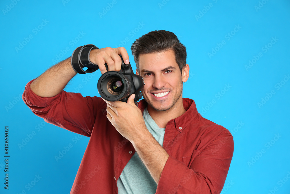 Fototapeta premium Professional photographer working on light blue background in studio