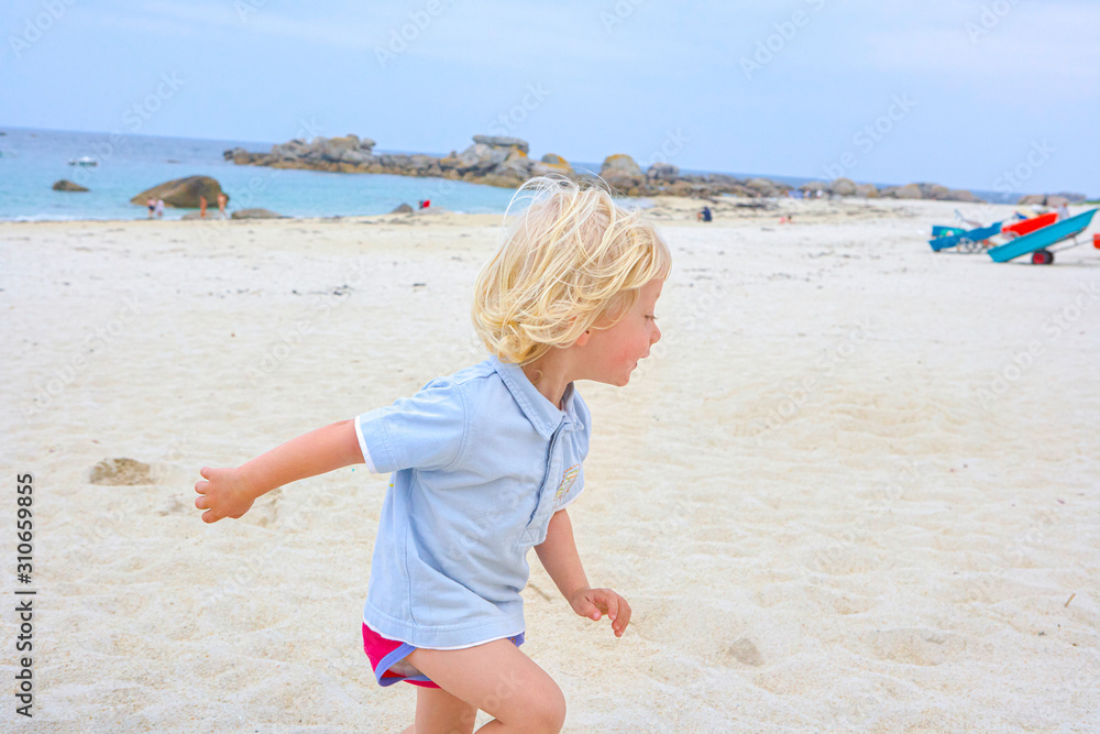Happy cute active little boy playing in the sand at a beach in Brittany Happy cute active little boy playing in the sand at a beach in Brittany