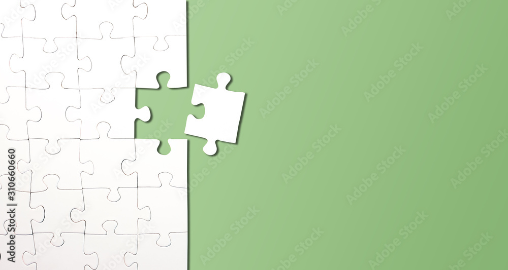 top view of jigsaw puzzle with one piece left on green background, completing a task or solving a problem concept - obrazy, fototapety, plakaty 