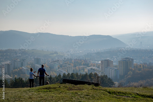 View from the hill on Sasova - part of town Banska Bystrica, Slovakia. Block of flats in valley. A couple with a doy enjoy beautiful view. photo