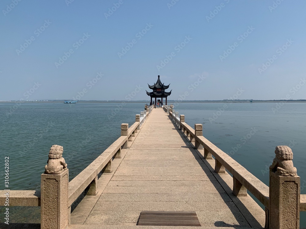 A pagoda at the end of a long jetty over water