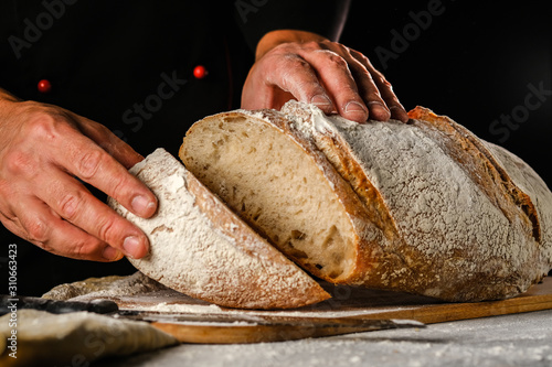 Man's hands holding baked bread - Cutting the bread 