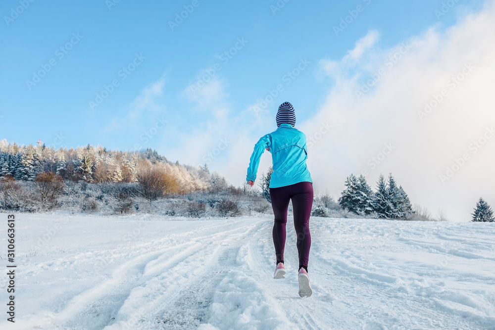 Running woman. Runner on the snow in winter sunny day. Female fi