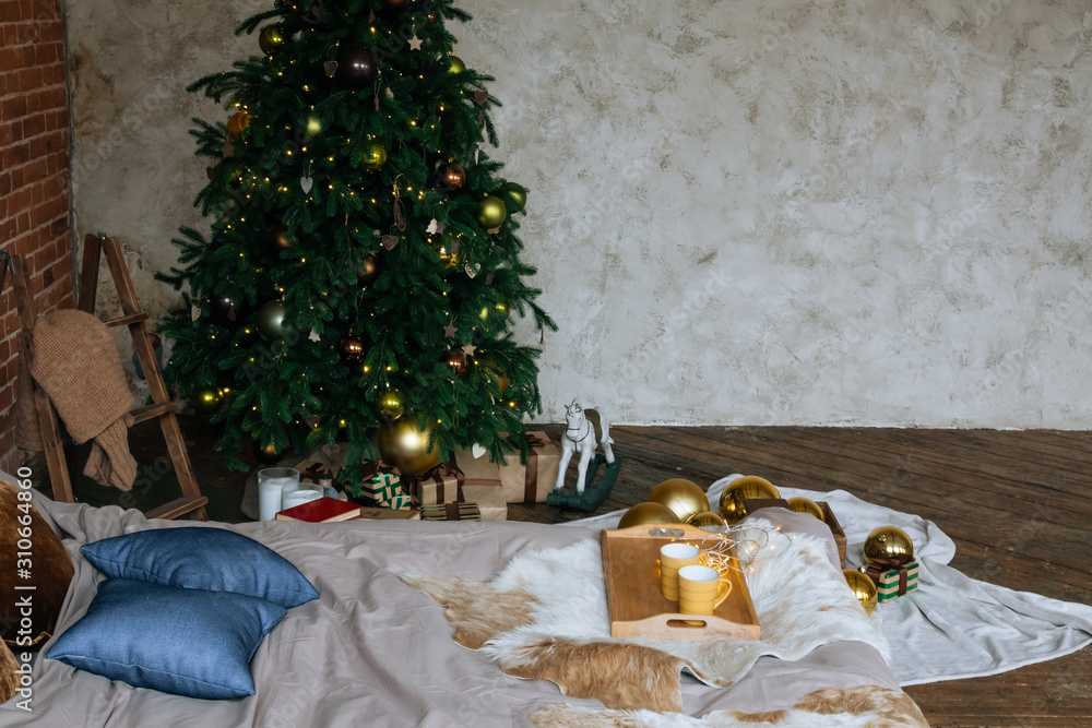 Stylish Christmas loft interior,cozy bedroom with wooden bed and a lot of lights with a decorated Christmas tree and a garland.