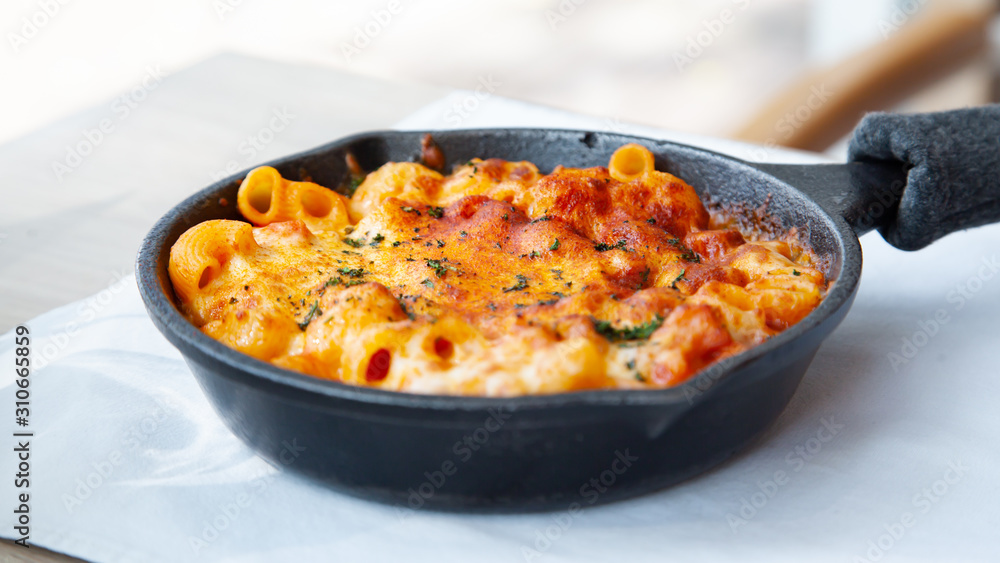 Baked macaroni and cheese with fresh tomato sauce served on hot pan Baked macaroni and cheese with fresh tomato sauce served on hot pan