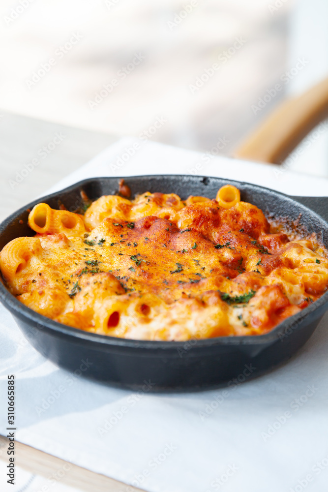 Baked macaroni and cheese with fresh tomato sauce served on hot pan Baked macaroni and cheese with fresh tomato sauce served on hot pan