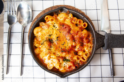 Baked macaroni and cheese with fresh tomato sauce served on hot pan