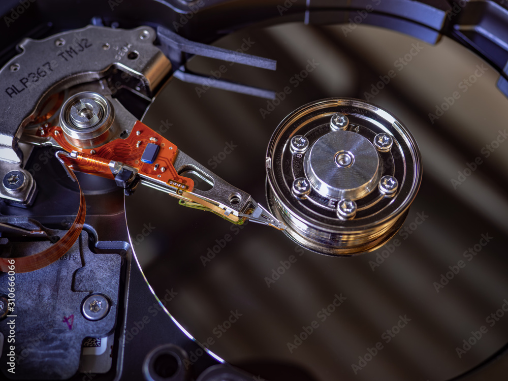 The old IDE hard disk internal components with a beautiful shiny magnetic disk. The old IDE hard disk internal components with a beautiful shiny magnetic disk.