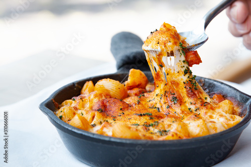Baked macaroni and cheese with fresh tomato sauce served on hot pan