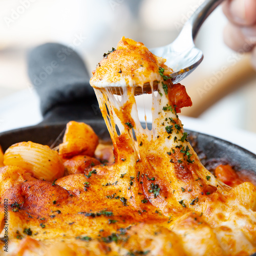 Baked macaroni and cheese with fresh tomato sauce served on hot pan