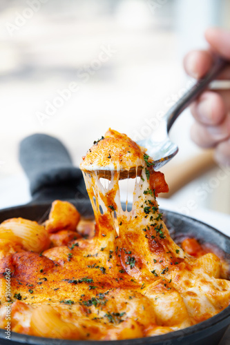 Baked macaroni and cheese with fresh tomato sauce served on hot pan