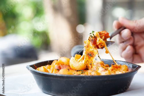 Baked macaroni and cheese with fresh tomato sauce served on hot pan