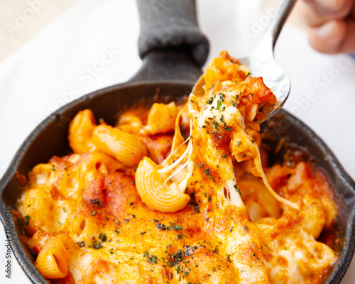 Baked macaroni and cheese with fresh tomato sauce served on hot pan
