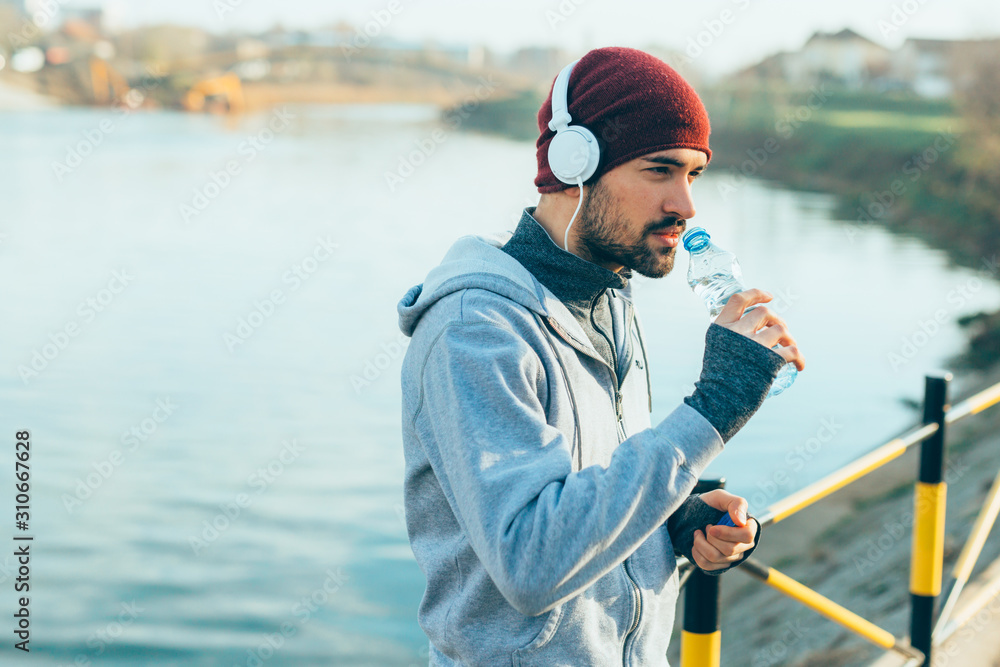 young man running outdoors, drinking water young man running outdoors, drinking water