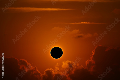 phenomenon of partial sun eclipse over silhouette orange cloud and sunset sky photo