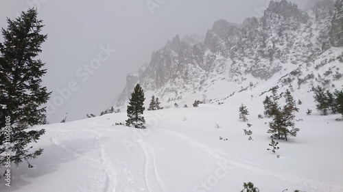 Alpine winter hiking trail tracks covered with snow stormy dark clouds with a faint sunshine