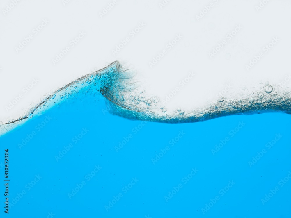 Wave of blue liquid against white background surface view
