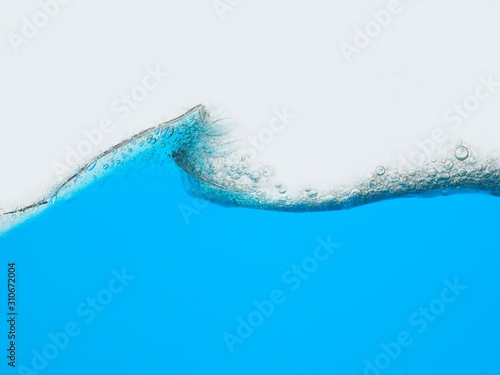 Wave of blue liquid against white background surface view © moodboard