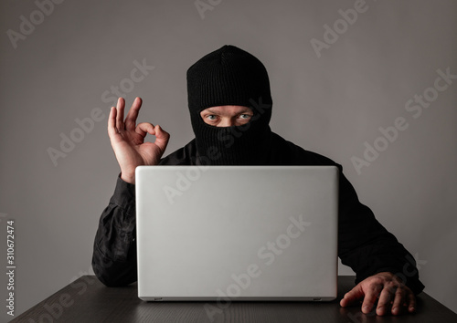 Hacker in mask using a laptop.