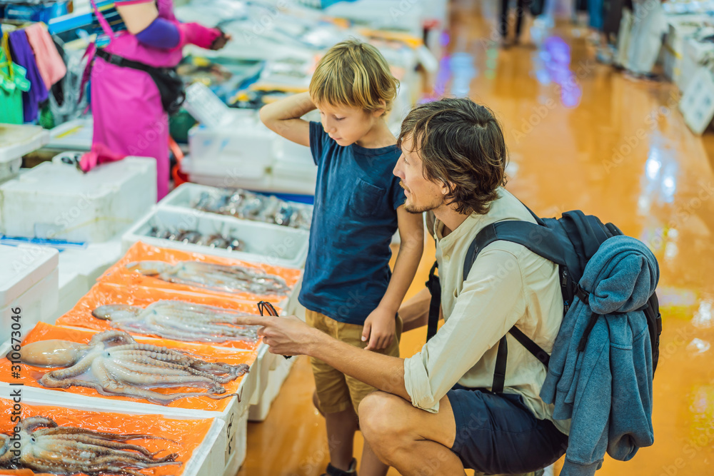 Dad and son in the Korean market. Raw seafood at Fisheries Wholesale Market in Seoul, South Korea. Traveling with children, concept Dad and son in the Korean market. Raw seafood at Fisheries Wholesale Market in Seoul, South Korea. Traveling with children, concept