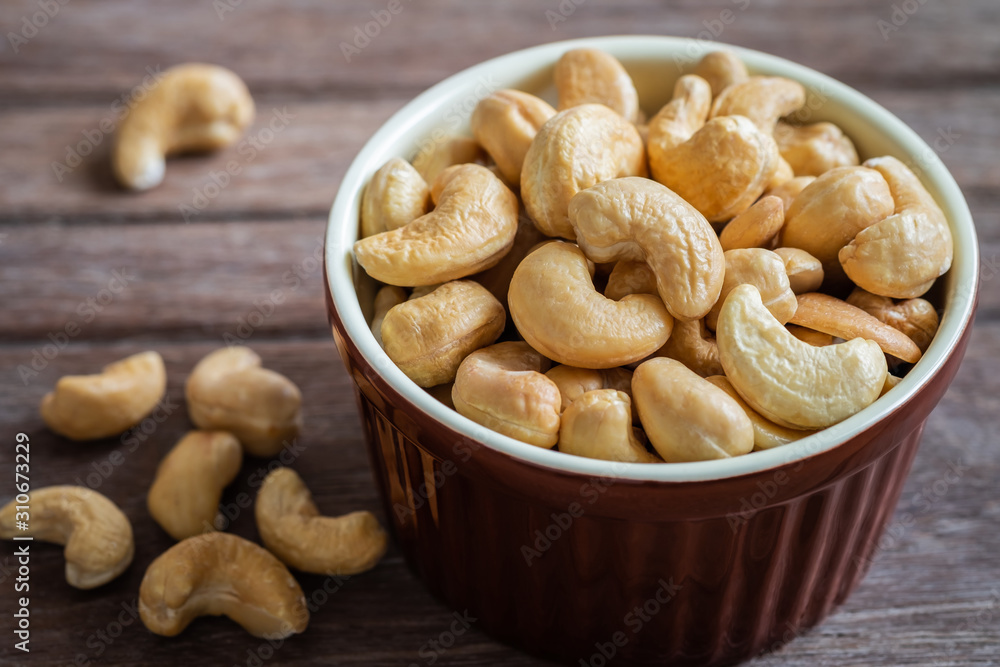 Cashew nut in brown bowl on wooden table Cashew nut in brown bowl on wooden table