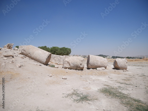 Remains of a tall fallen pillars of the ruins of the Roman site of Amman Citadel on a hill in the city center of the capitol of Jordan
