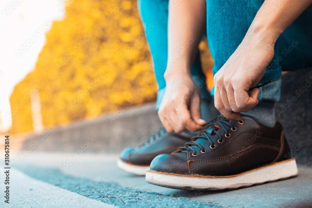 image of man is shoelace on wearing brown leather shoes image of man is shoelace on wearing brown leather shoes